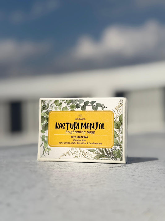 Kasturi Manjal Brightening Soap packaging on a concrete surface with a blurred background